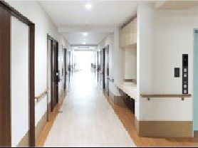 廊下はまっすぐで両サイドに手すりと居室ドアがあり、手前には車いす対応の洗面所がある。
