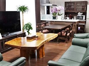 木製のテーブルとソファ類が並ぶダイニングと奥のほうに食事をとるためのリビングがある部屋
