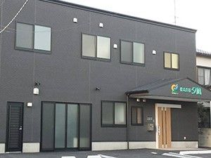シックな色合いの外観のサービス付き住宅の外観。雨除けのひさしがあるエントランス