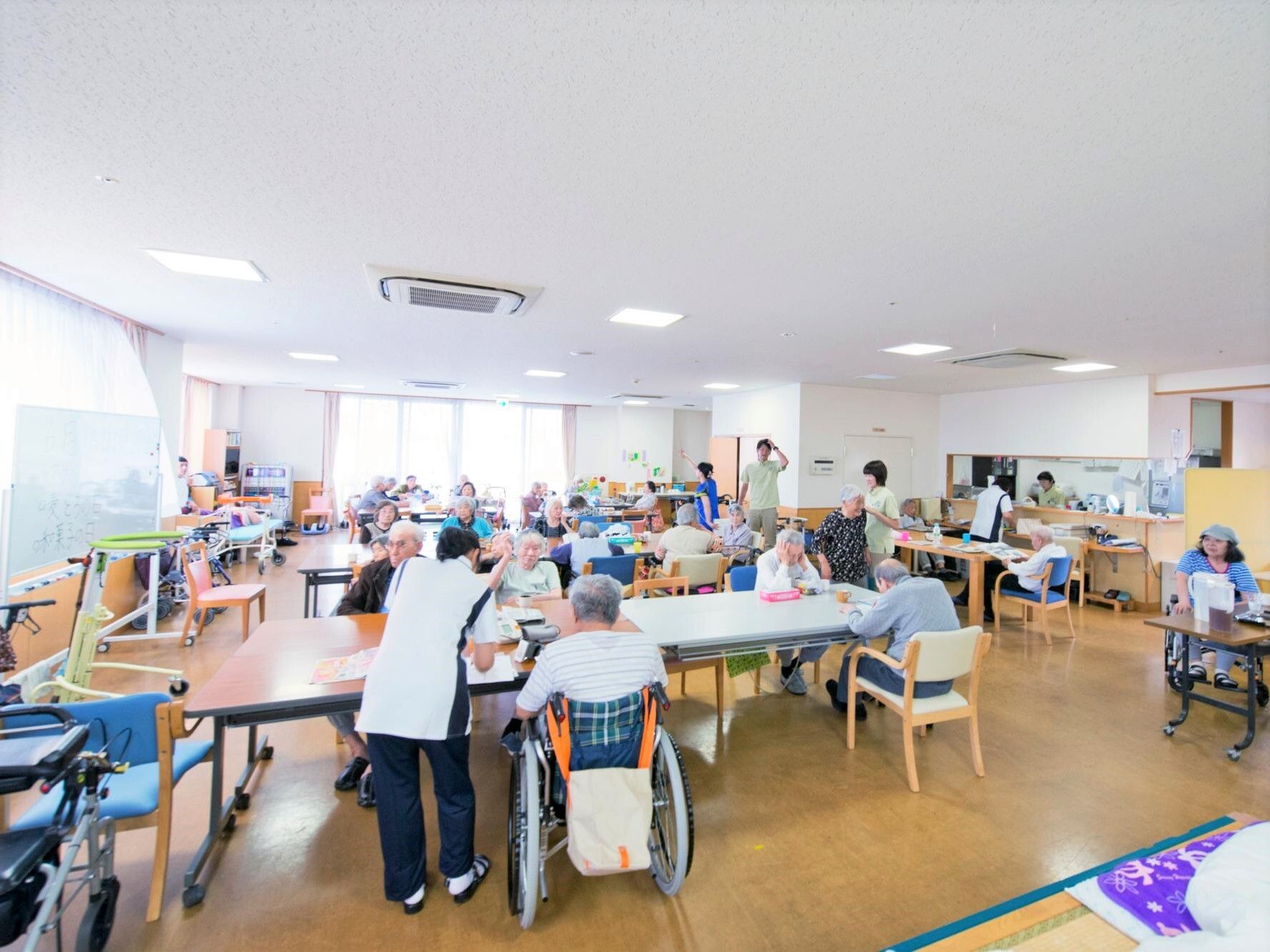食堂に集まり食事を楽しむ入居者たちと、サポートに当たっているスタッフ。