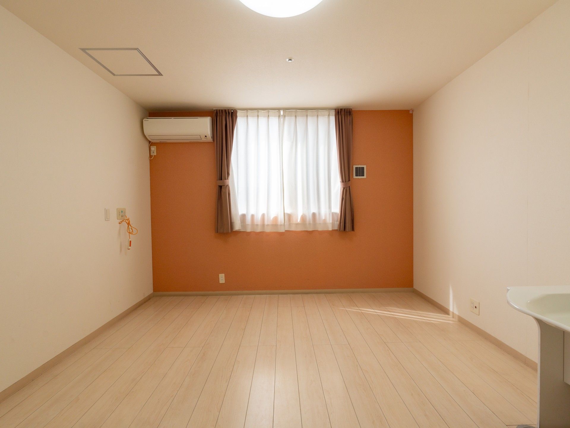 ボーダー柄のエプロンを付けた女性スタッフが笑顔で高齢男性が立ちあがる介助をしている。