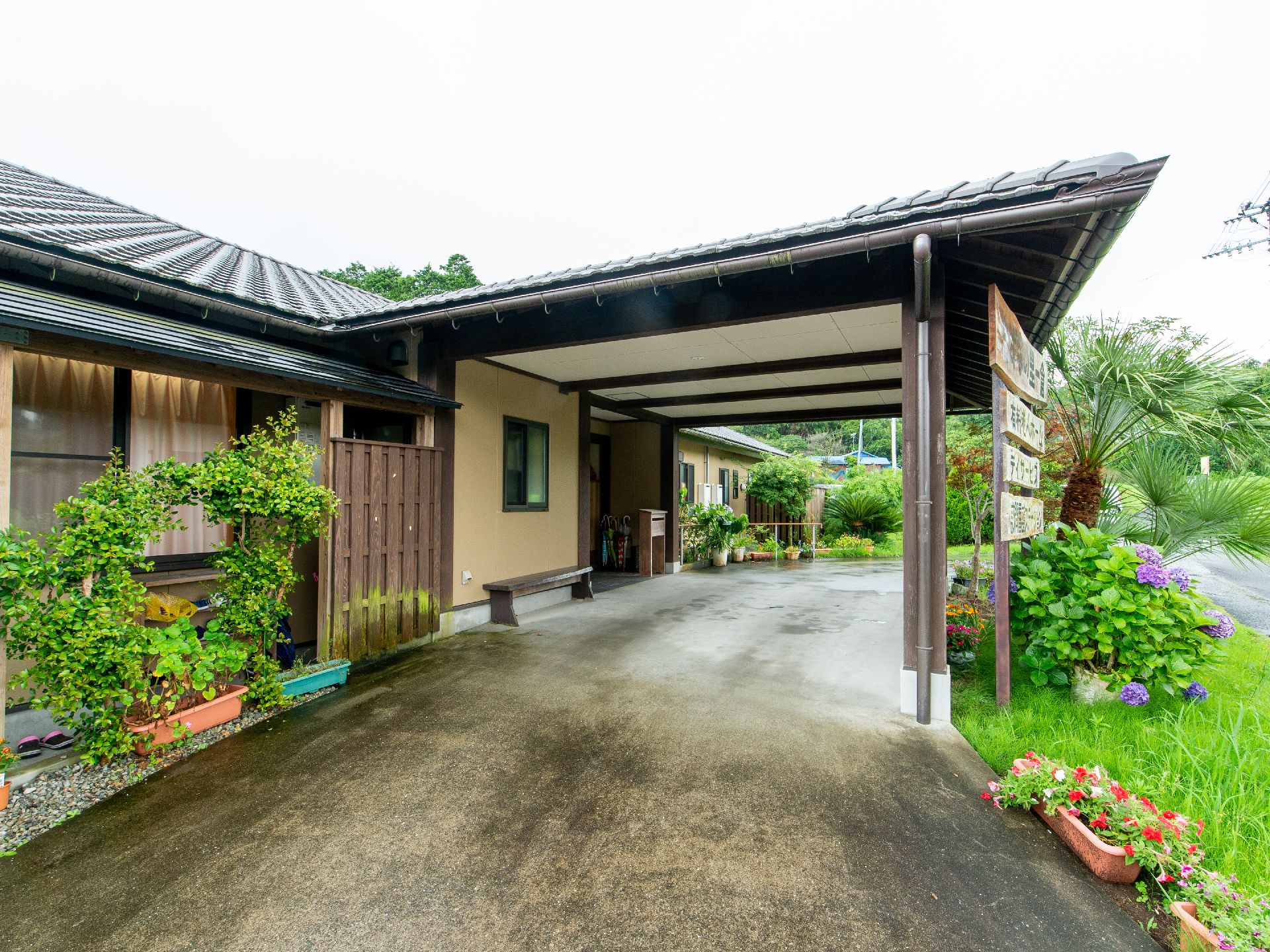 庭に緑や花があふれていて、車寄せが玄関前にある日本家屋