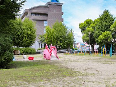 ピンクや黄色のカラフルな遊具が置かれている公園があり、木もたくさん植えられている。
