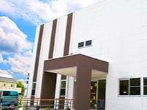 白を基調とした２階建ての建物は日当たり良好でブラウンのアクセントが入っていて、駐車場がある。