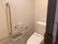 縦横にベージュの手すりが付いているトイレには操作ボタンの横に呼び出しボタンも付いている。