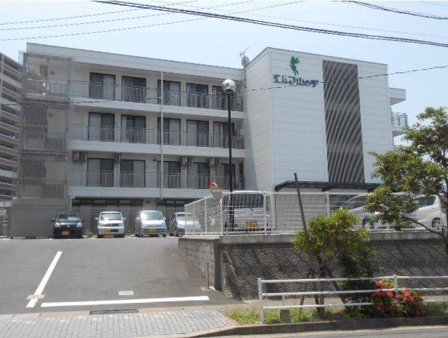 4階建ての建物は日当たりのいい場所にあり、敷地内には駐車場がある。周りには緑も植えらえている。
