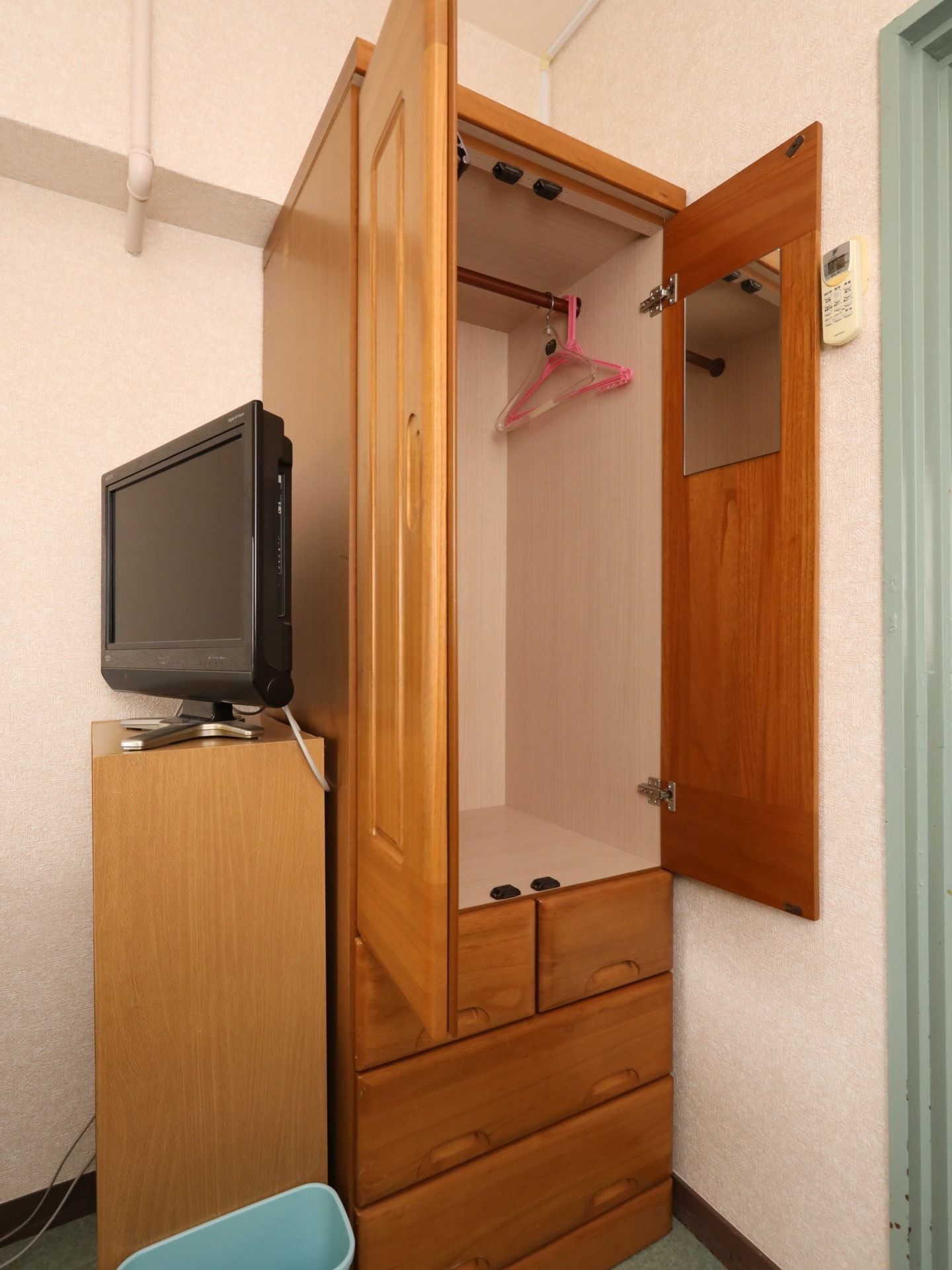 部屋に備え付けられている木製のクローゼットには、ハンガーポールやサイズの異なる引き出しが設置されている。