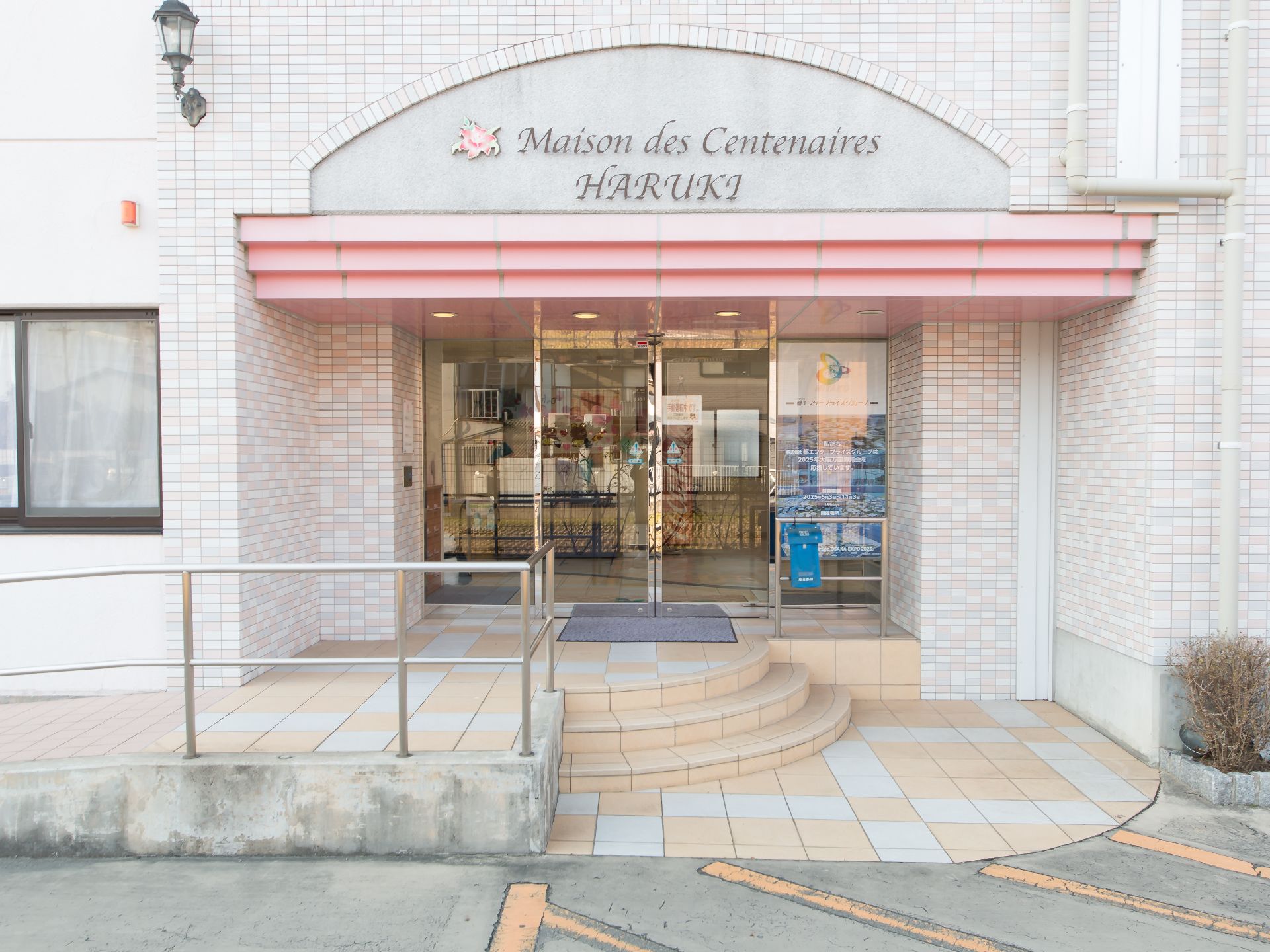 玄関までの通路は、階段のほか手すり付きのスロープが設置されている。扉は、ガラス張りの自動ドアになっている。