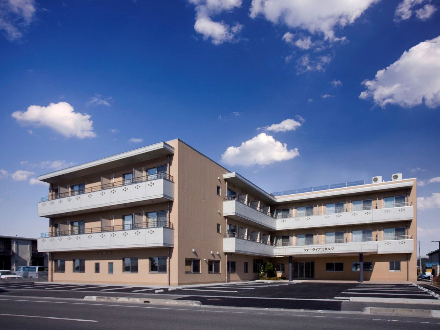 3階建ての建物はエル字型でブラウン系。日当たりのいい場所に建っていて、周りには背の高い建物がない。
