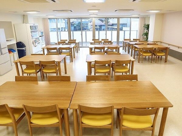 木製の4人掛けのテーブルセットが並んだ食堂には自動販売機や冷蔵庫が置かれ、カラフルな分別用のゴミ箱も設置されている。