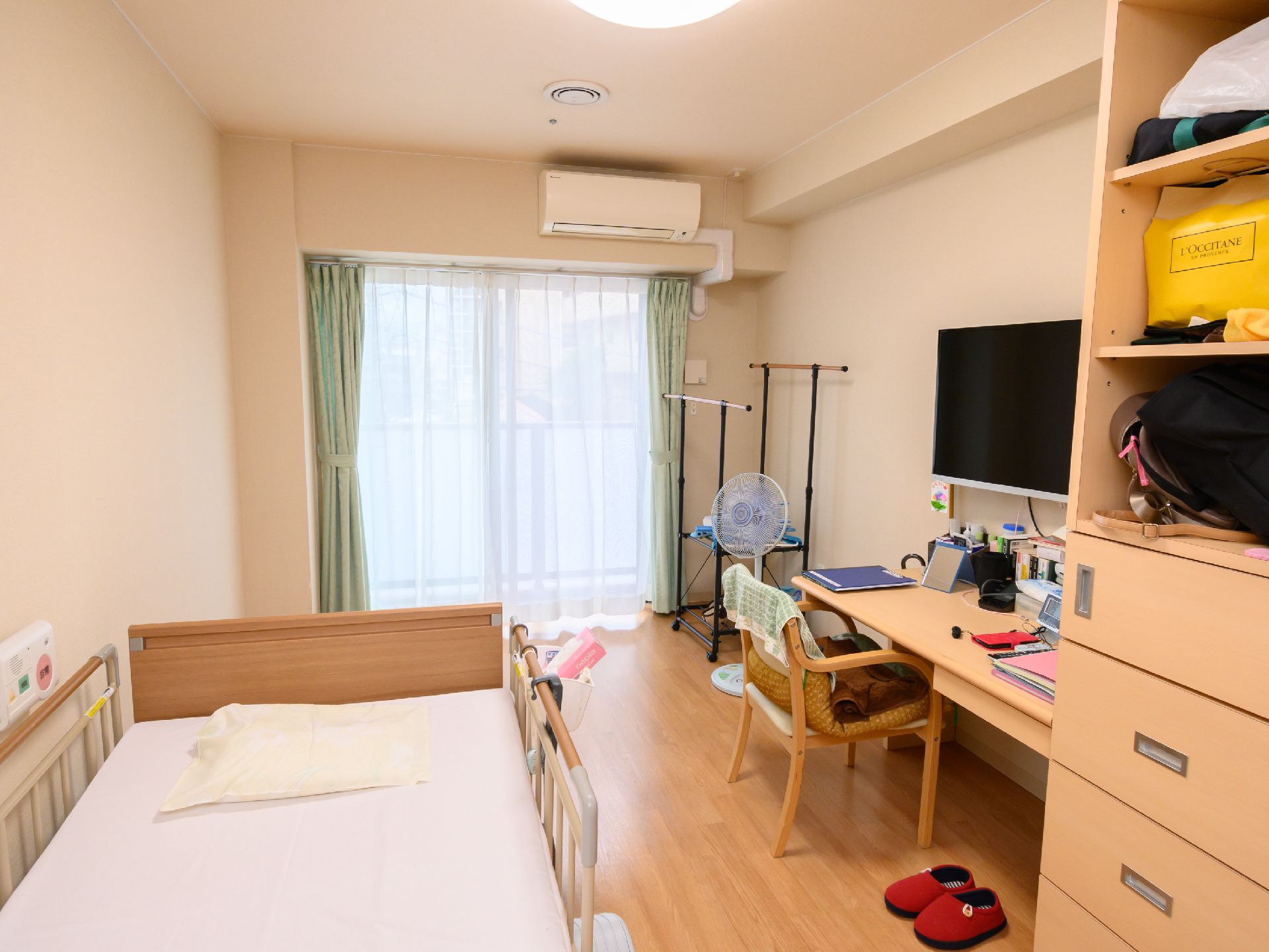窓から日差しが入り、家具や介護ベッドが置かれている居室