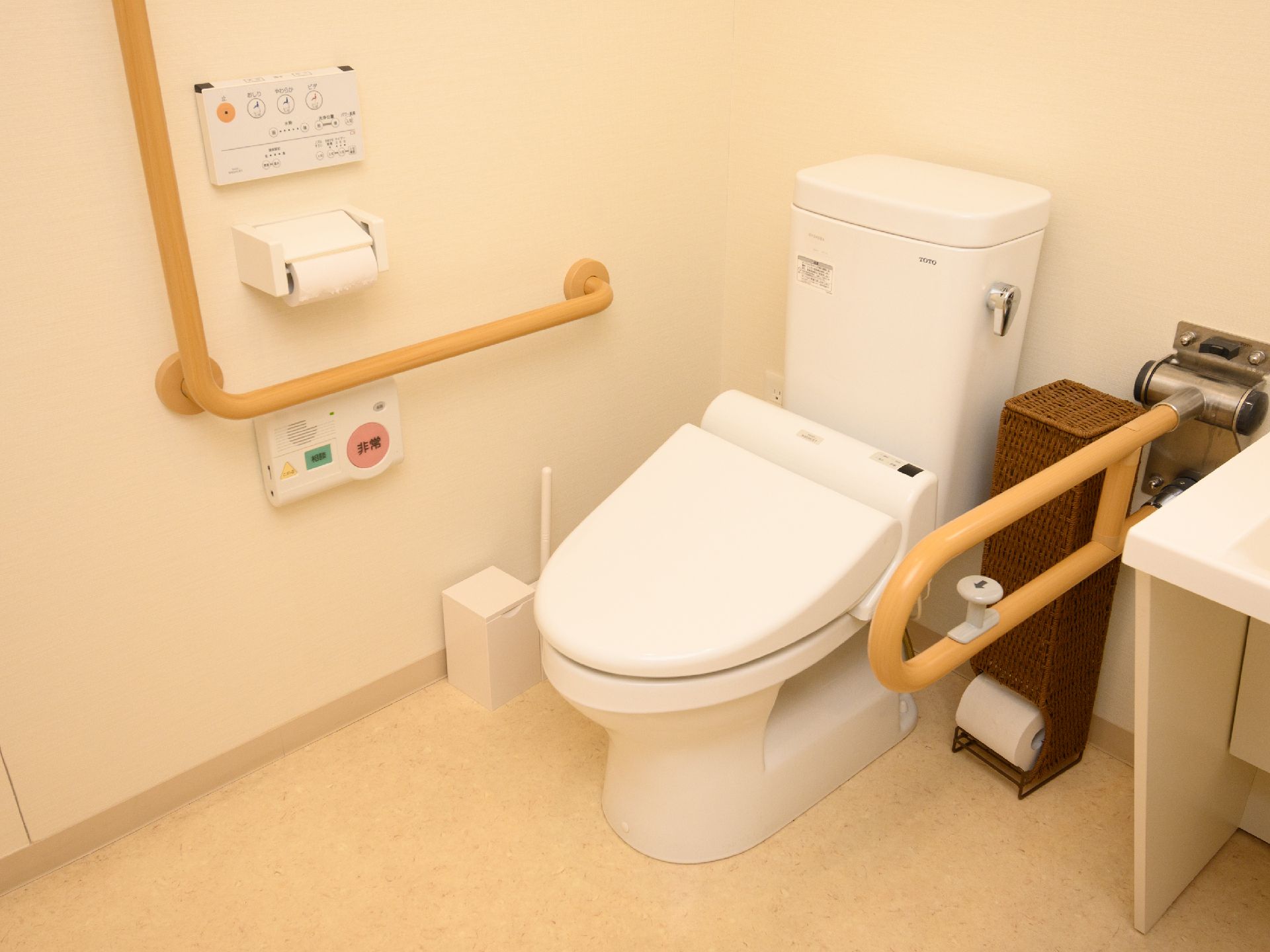 バリアフリー完備で、便座と洗面台の周りに手すりが設置されているトイレ