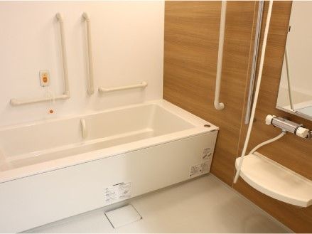 呼び出しボタンが設置された浴室には一人用の浴槽とシャワー、手すりや鏡がある。