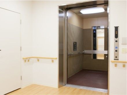 手すりや鏡が付いた大きなエレベーター。エレベーターの扉のそばまで手すりが設置されている。