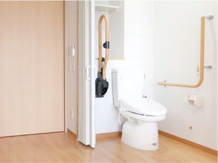 トイレには呼び出しボタンと収納スペース、手すりが付き、アコーディオンカーテンで仕切るタイプ。