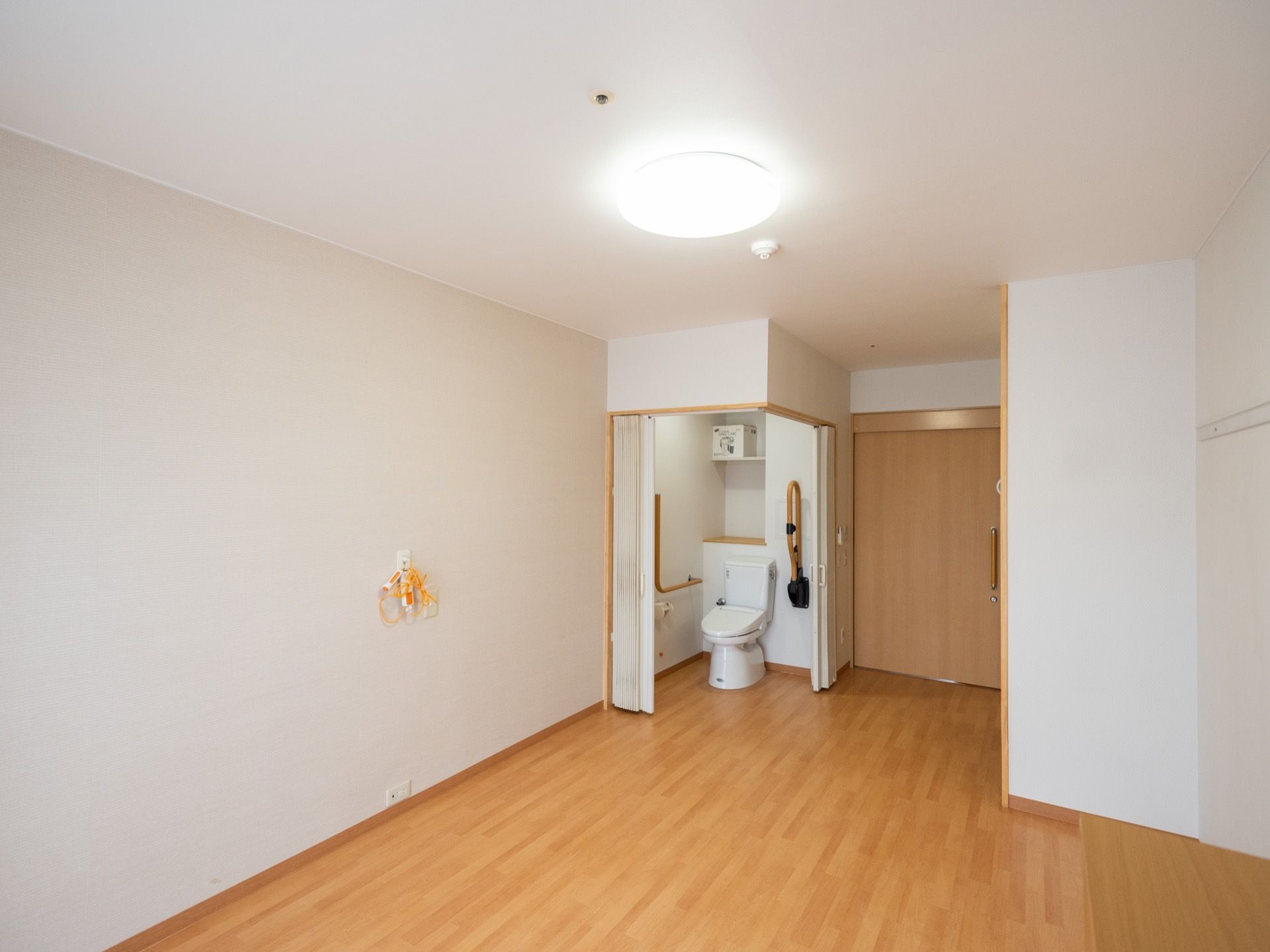明るく開放感のある居室である。入口ドアの横にはトイレスペースが設置されている。照明器具やケアコールも取り付けられている。