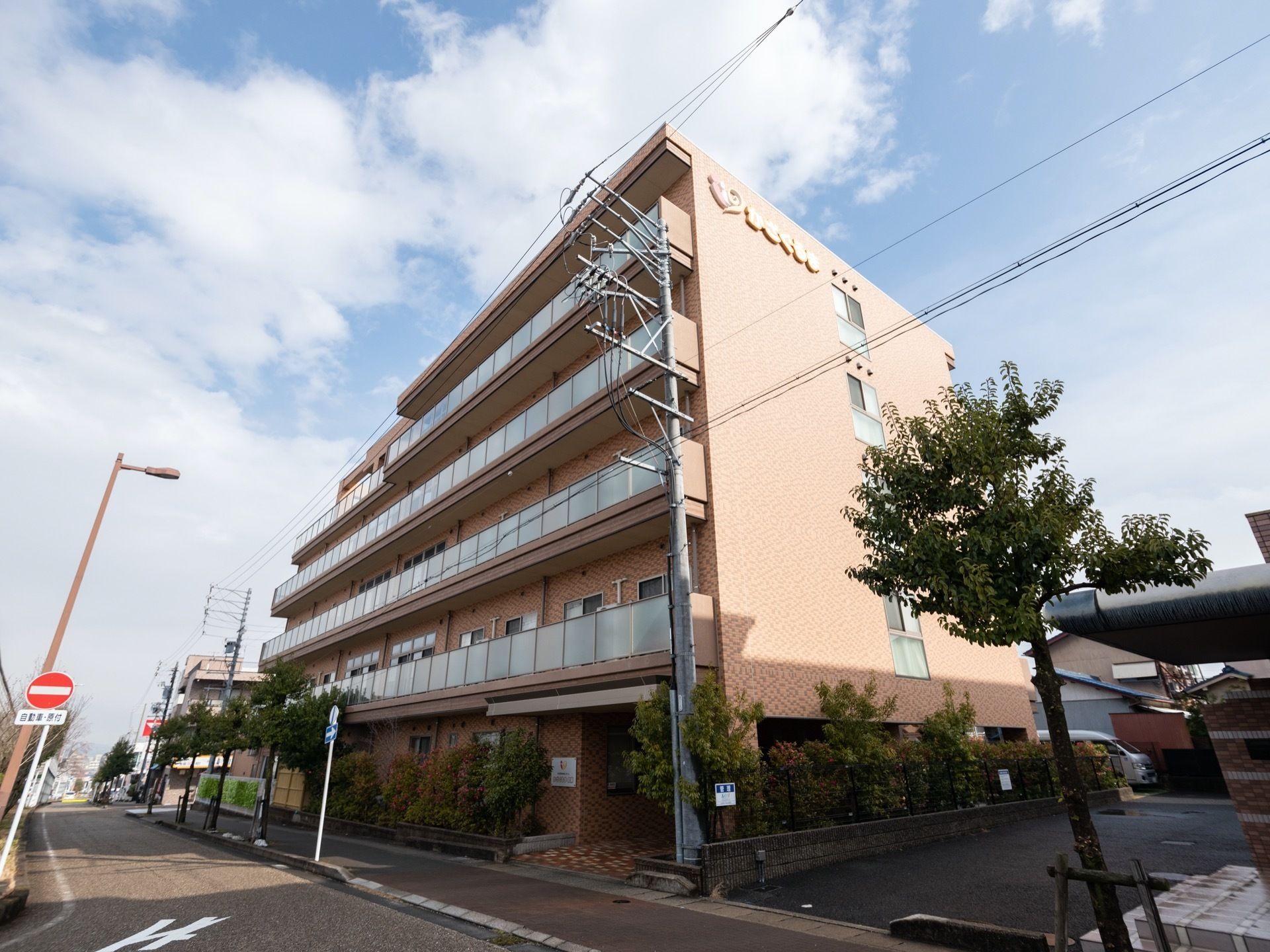 2階以上にパネルを取り付けたバルコニーが設置されている5階建ての施設建物である。道路に面し、開放感がある。