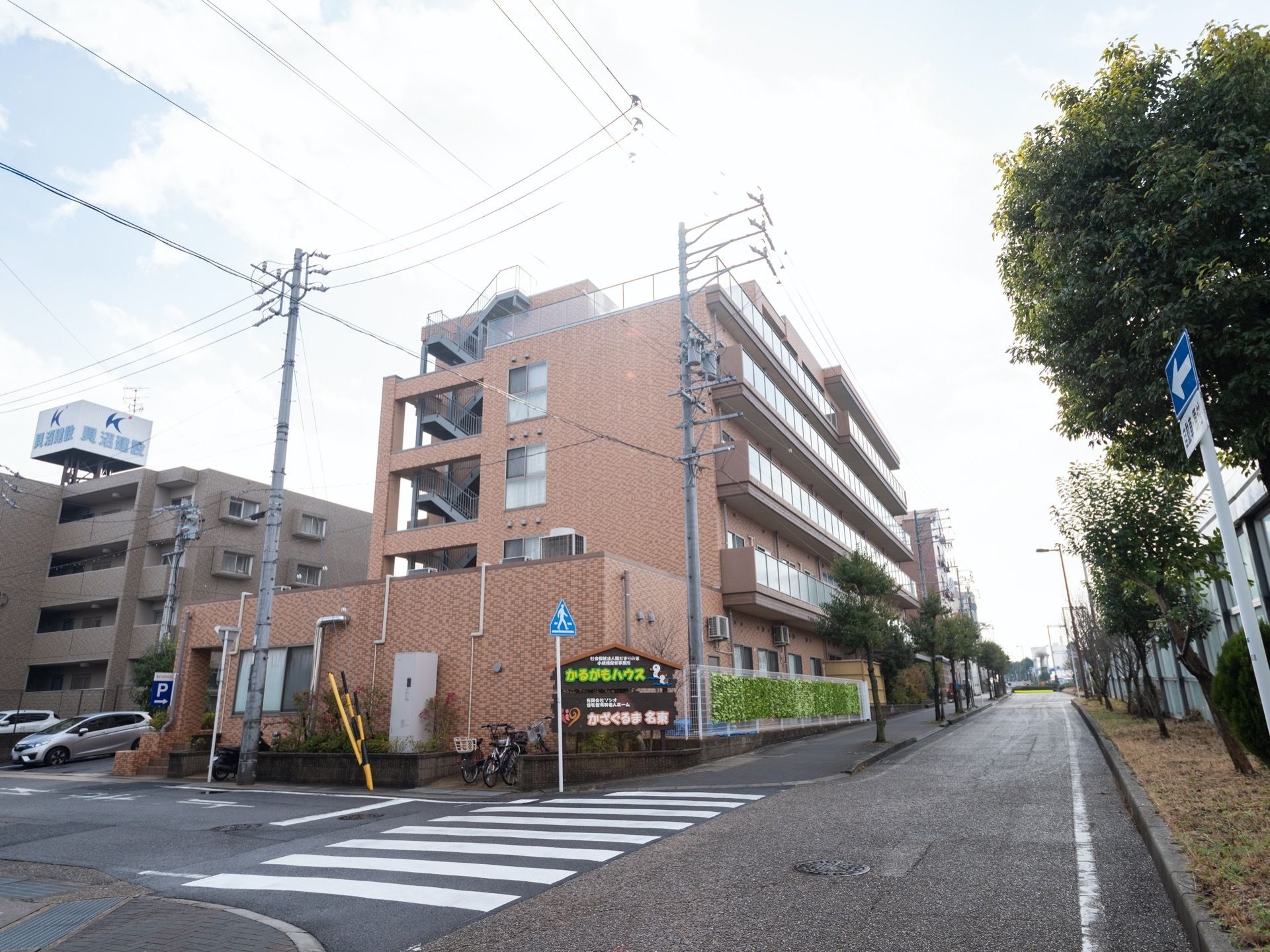 茶系のレンガ造りを思わせる5階建ての施設建物である。角地に立地し、建物に沿った道路は幅広い。歩道部分には、樹木が植わっている。