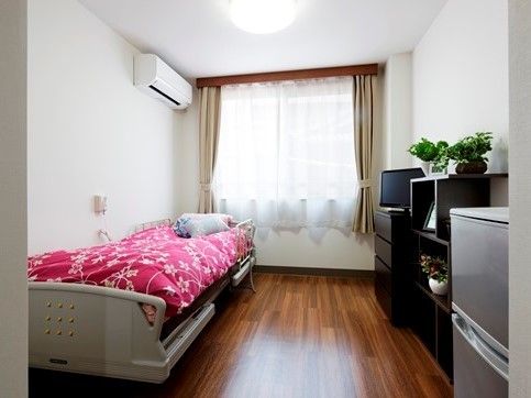 ベッドやエアコン、収納家具が置かれた居室。居心地のよさそうな雰囲気の部屋で日当たりもよい。