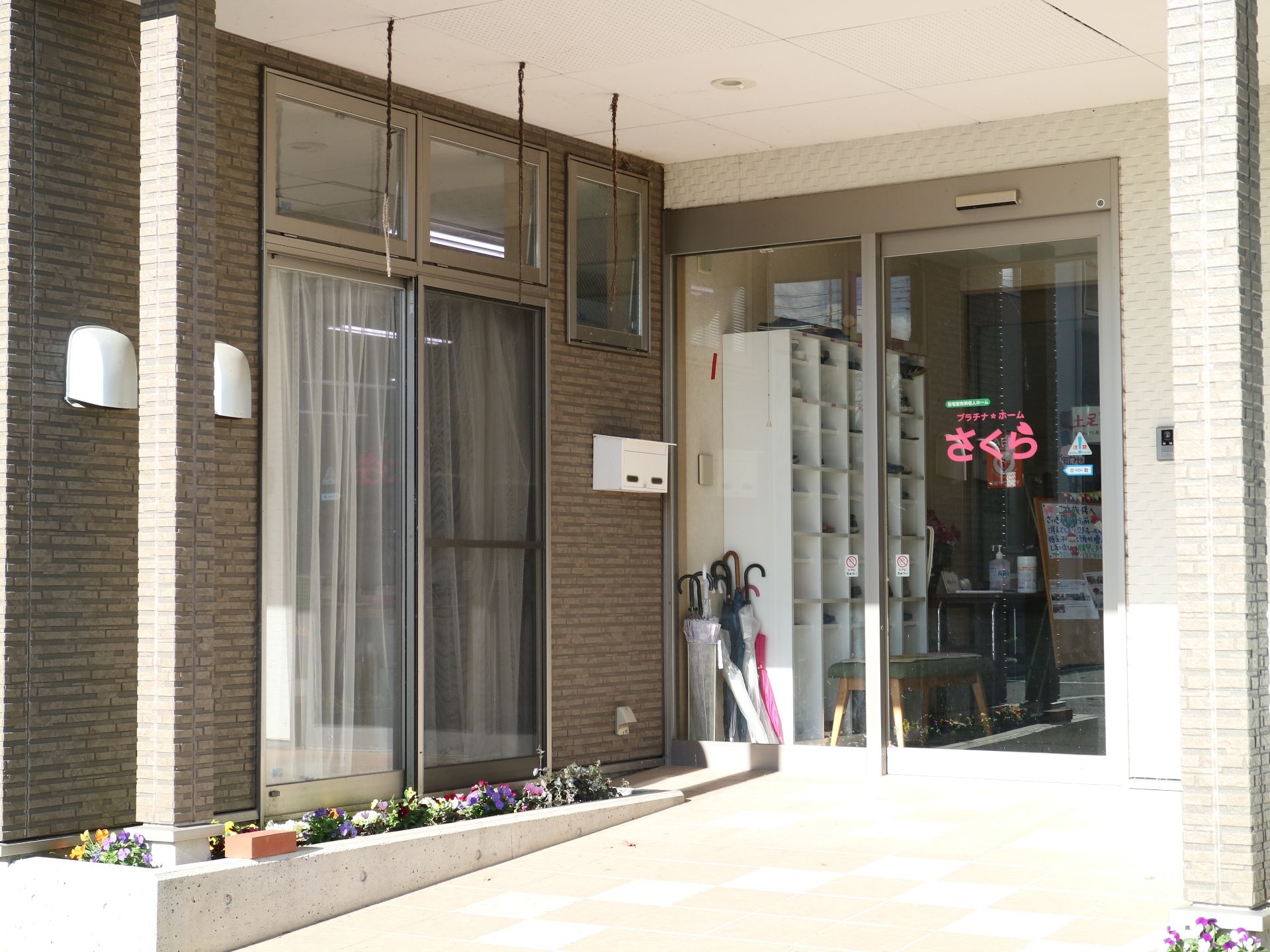 なだらかなスロープになっており、花が植えられた小さな花壇のあるエントランス