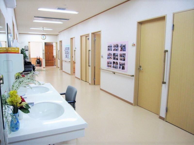 幅の広い廊下の様子。手前に洗面台、右側に個室のドアが写っている写真