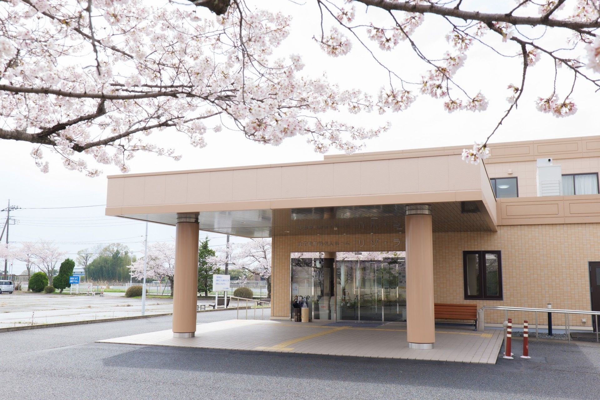 ブラウン系の建物は重厚感があり、玄関には大きな車寄せがあり、手すり付きのスロープやベンチがある。