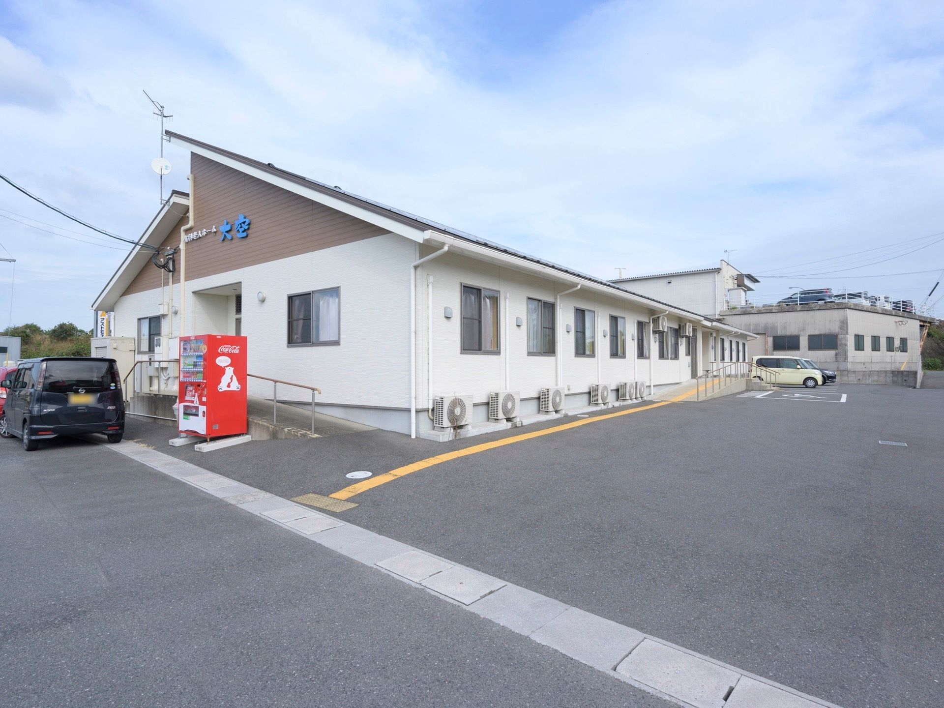 白を基調とした平屋建ての建物で、玄関までのアプローチには点字ブロックが設置されている。外壁沿いに複数のエアコンの室外機が置かれている。