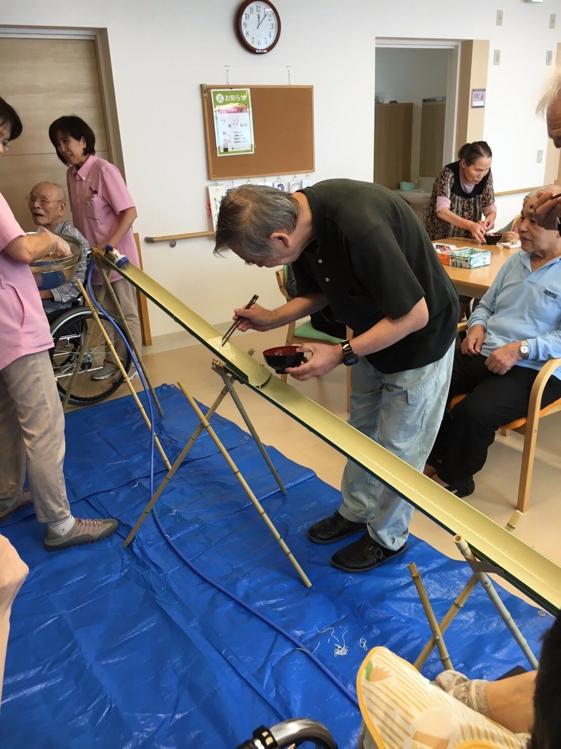 室内でそうめん流しを楽しむ入居者。男性がそうめんを取ろうとしている様子。