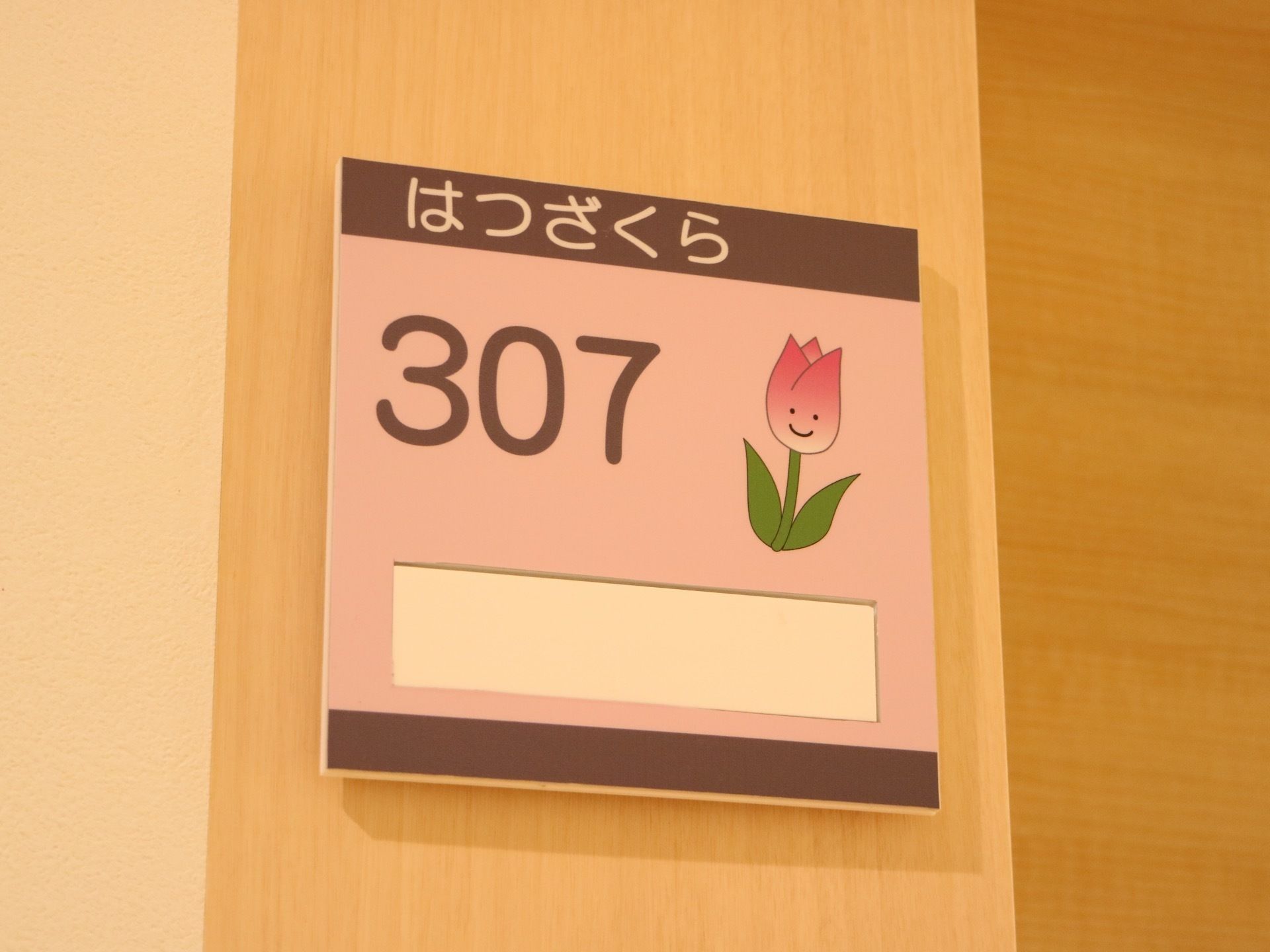 居室の出入口に、居室ナンバーが記されたプレートが設置されている。花の名前も書かれてあり、イラストも描かれている。
