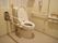 ホワイトを基調とした、清潔感ある洋式トイレである。両サイドに手すりが設けられている。ナースコールもある。