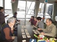 大きな共有スペースのテーブルでレクリエーションを楽しむ入居者たち。窓が大きく明るい雰囲気。