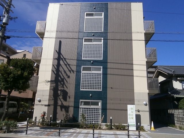 4階建ての建物を側面から見た様子。ベランダが付き建物の前にはホームの看板がある。