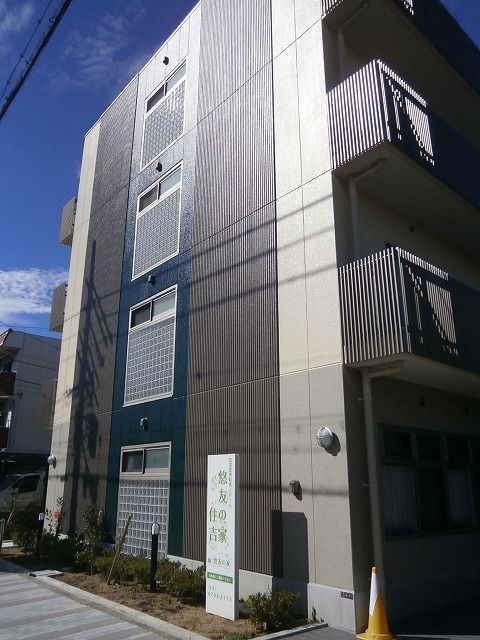 ４階建ての建物のすぐ前にはホームの看板があり、グレーやブルーの外壁はスタイリッシュな雰囲気。