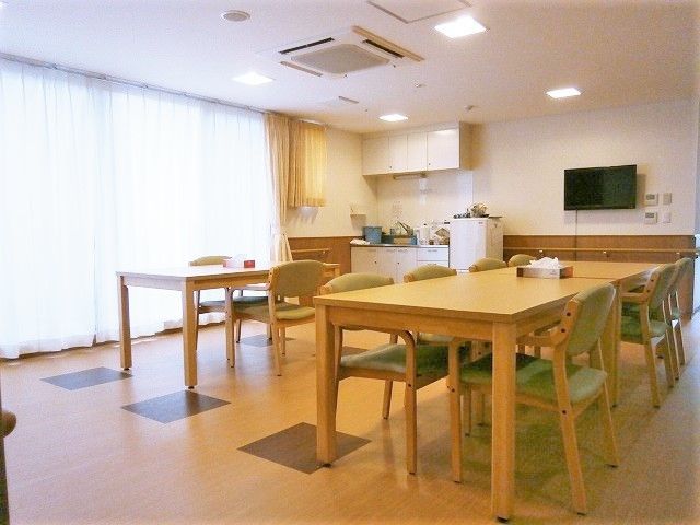 木製のテーブルが複数設置された広い食堂にはキッチンもあり、壁掛けテレビも設置されている。