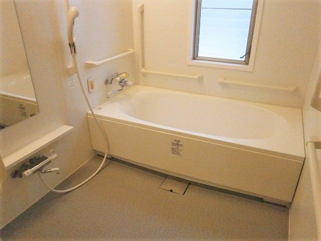 シャワー付きの浴室には一人用の浴槽があり、手すりと窓が付いている。