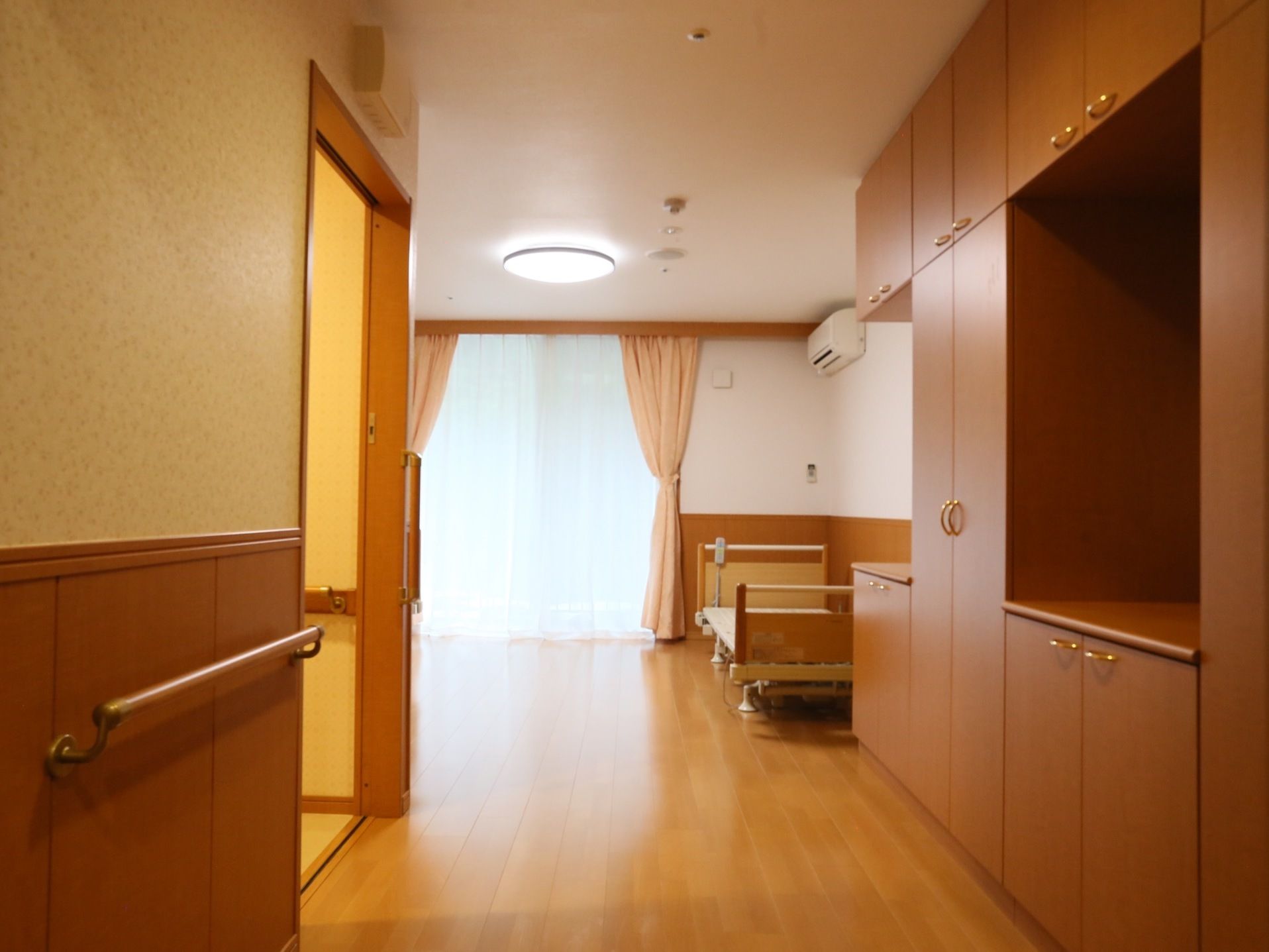 壁には手すりがあり、トイレはスライド式のドアになっている。介護用のベッドが設置されバリアフリーを考慮した部屋となっている。