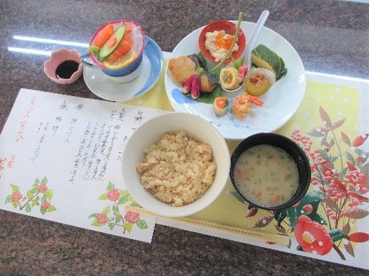 食事の写真、色とりどりのおかずがあり、お品書きや、きれいなマットが敷いてあり華やかな見た目