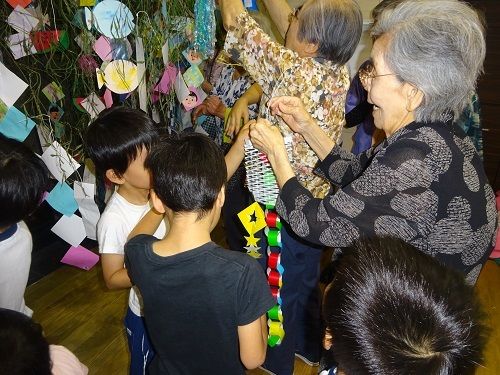 利用者と園児が一緒に七夕飾りを作る様子