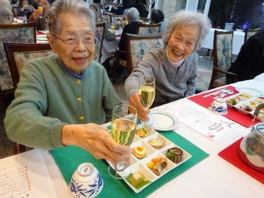 ご利用者が食事をする様子。グラスを持って笑顔で乾杯をしている