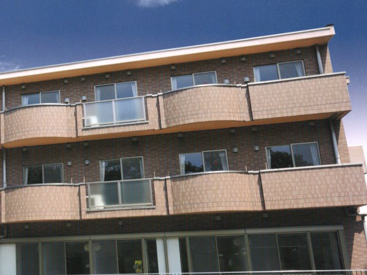 角フロアにベランダが付いたブラウン系の建物。外壁はレンガ調で、落ち着いた雰囲気。