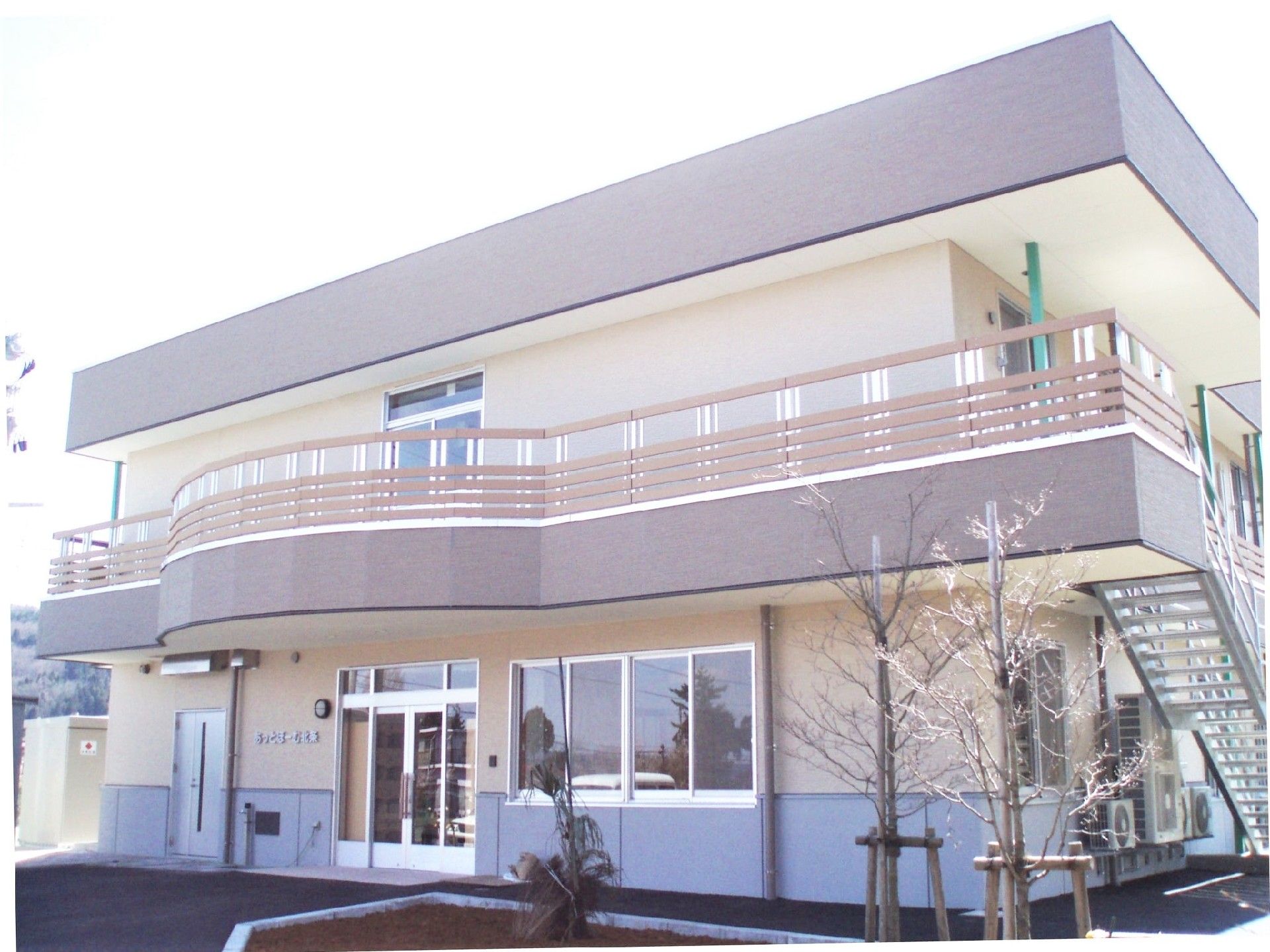 2階建ての建物はベージュやブラウンを使用し温かい雰囲気。屋外階段やベランダが付いている。