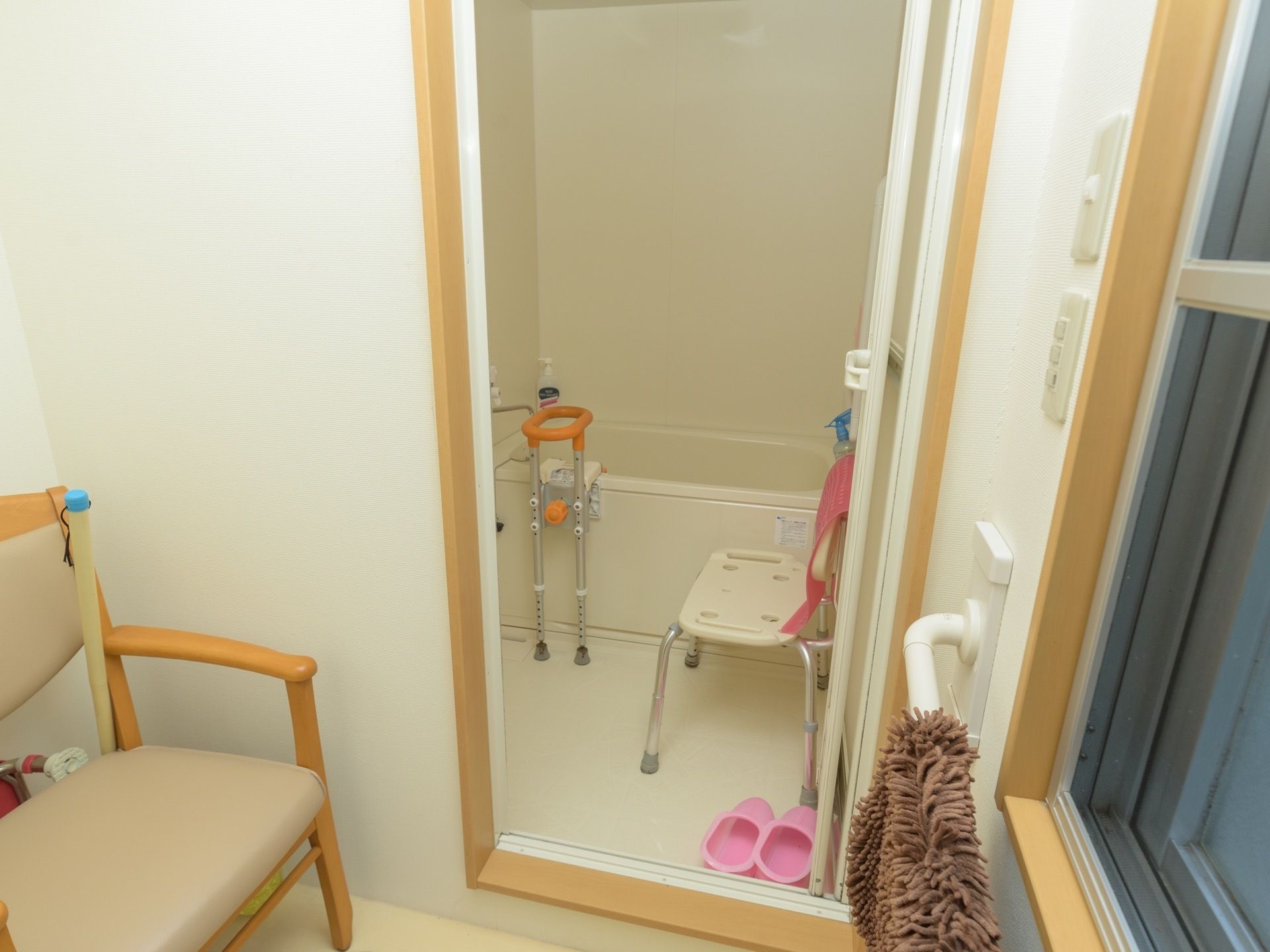 一般家庭向けの浴室で、浴槽には取り外しや高さ調整が可能な手すりが設置されている。洗い場にはシャワーチェアが置いてある。