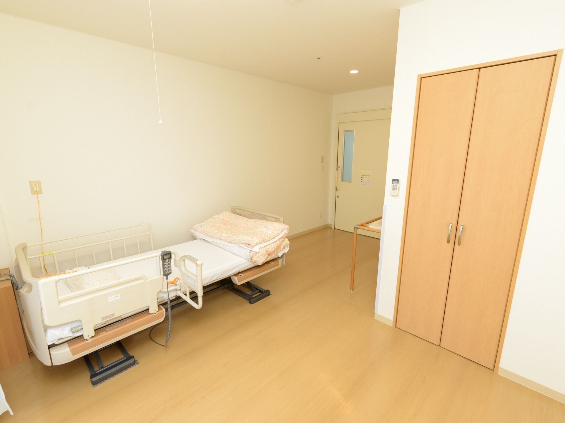居室のドアをまっすぐ進んだところに電動ベッドが置いてあり、室内にはクローゼットが取りつけられている。