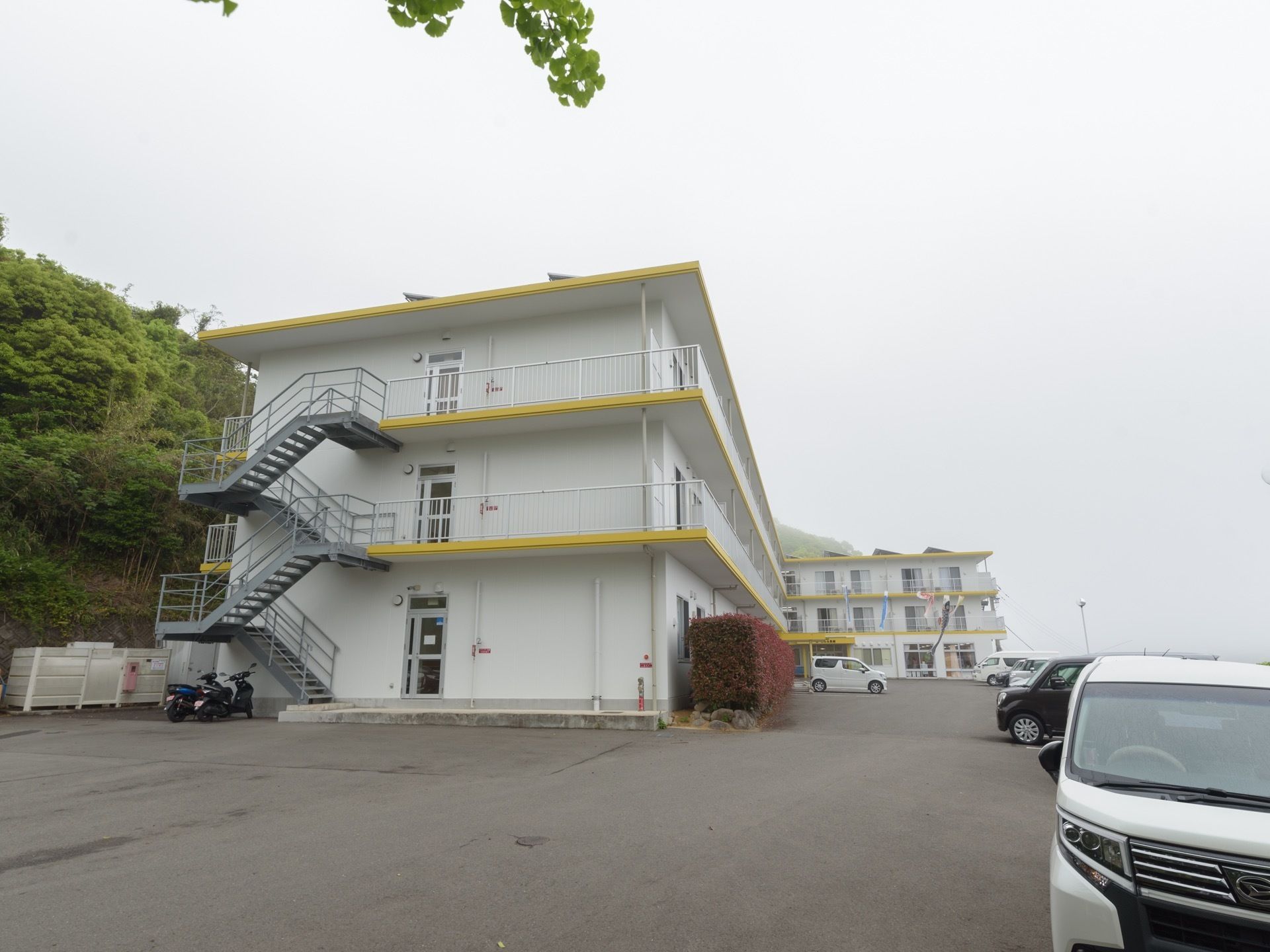 L字型の建物で全体的に白く、ベランダの部分が黄色く色がついている。玄関の近くに、鯉のぼりが飾ってある。