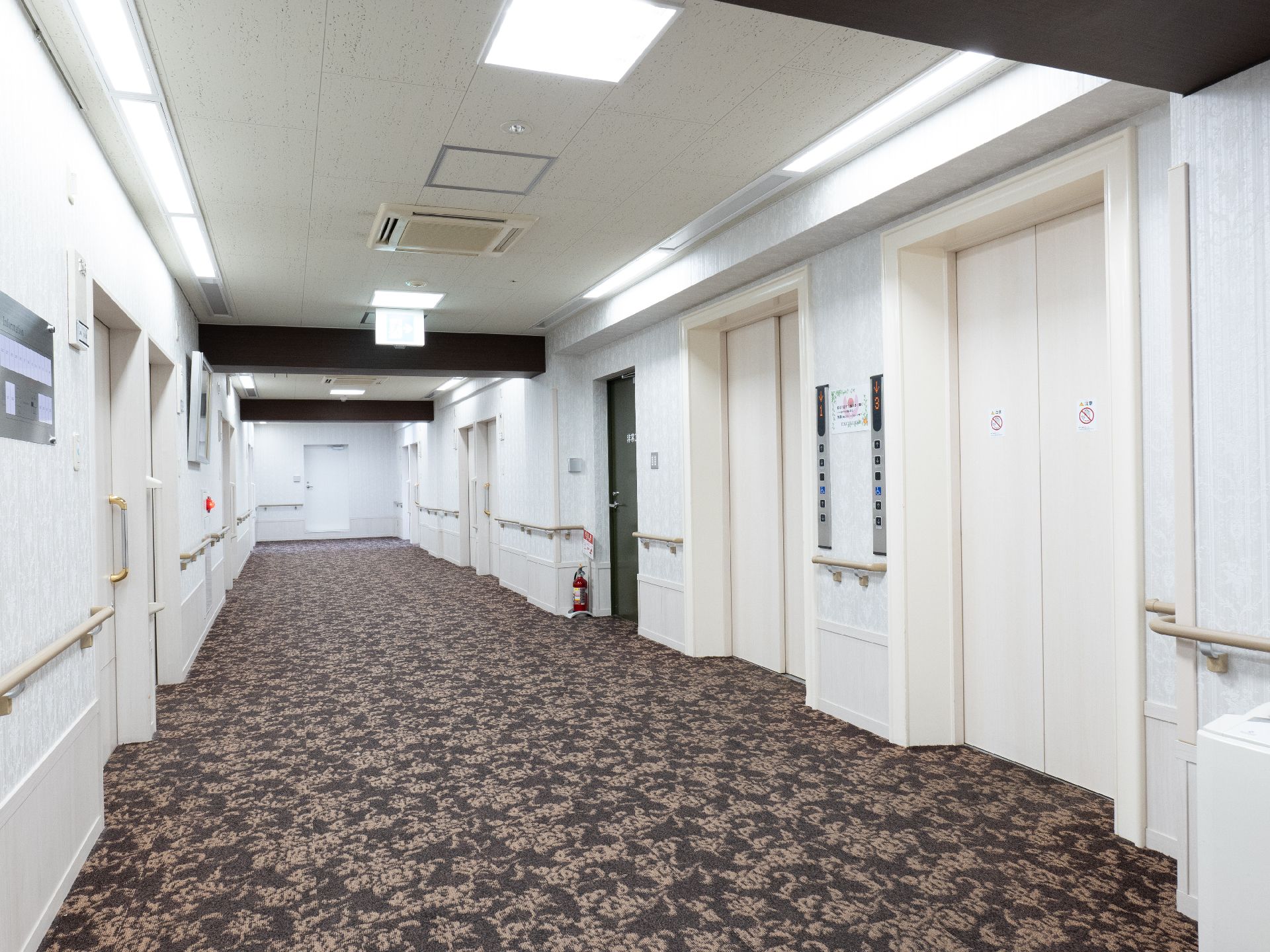 両側の白い壁に手すりが付いた直線の廊下