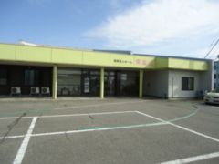 駐車場がある施設の敷地内。広めの敷地内に平屋建ての建物がある様子
