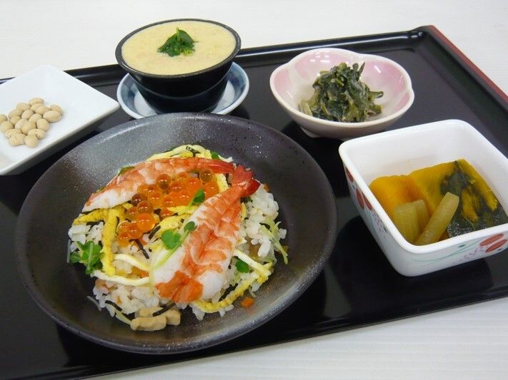 野菜の和え物や煮物、茶碗蒸し、乾燥大豆、海老やイクラが乗ったちらし寿司がある。