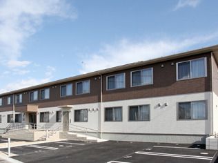 日当たりのいい場所に建っている２階建ての建物は玄関に屋根があり、手すりが付いたスロープがある。