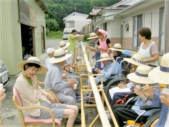 屋外の芝生の上に座って楽しそうに話をしている高齢夫婦と女性の姿