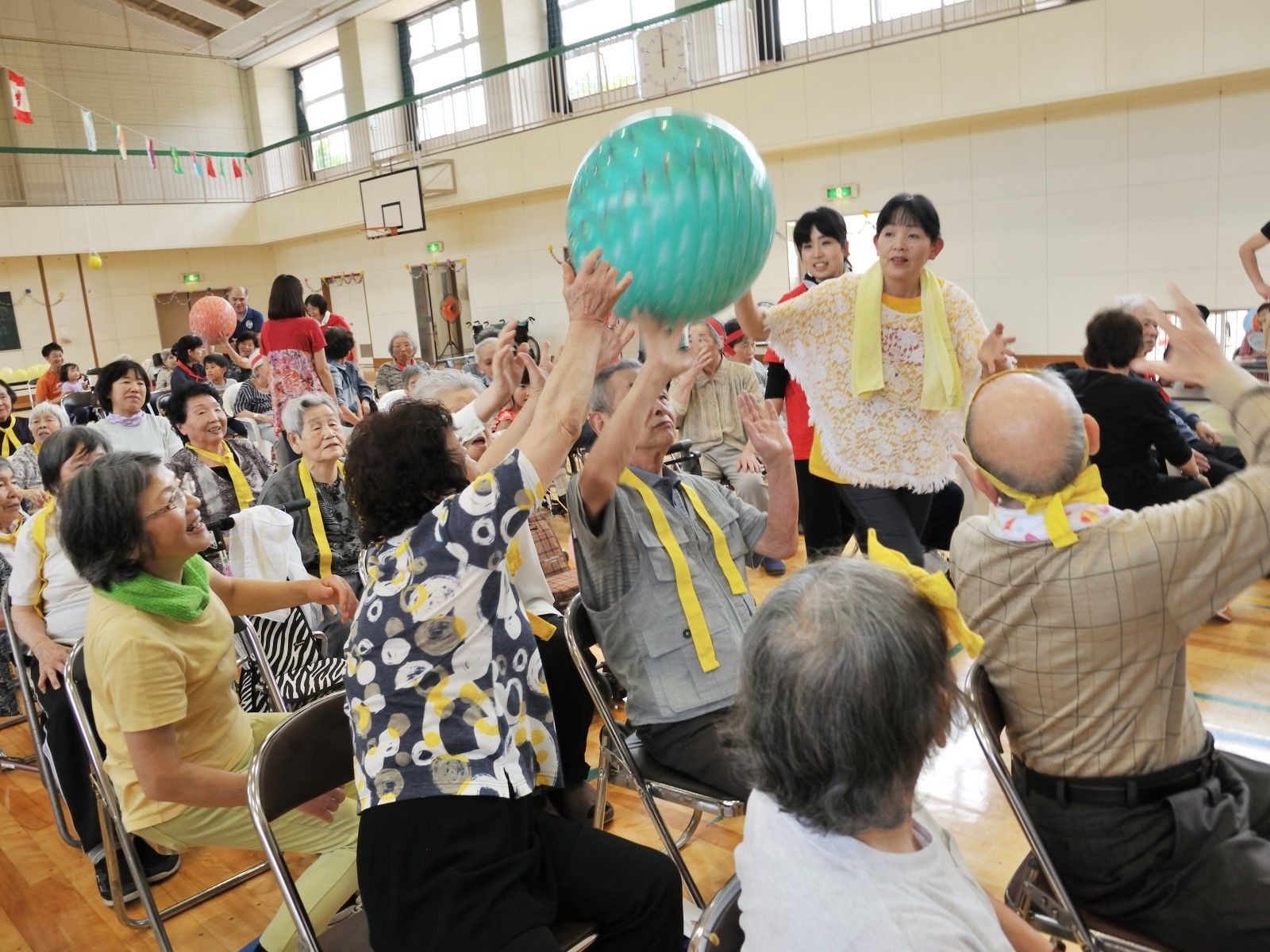 大きなビニールのボールを運ぶ高齢者。施設の運動会を写した写真